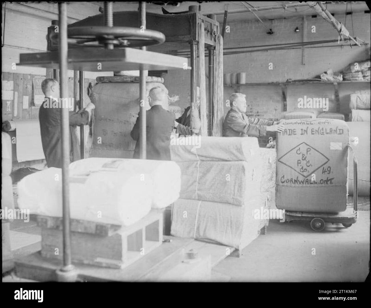 Huddersfield Tuchfabrik - die Arbeit von C und J Hirst und Söhne Ltd., Sunnybank, Longwood, Huddersfield, Yorkshire, England, UK, 1943 Stücke Stoff verpackt, drückte fest von einer großen Presse, und dann gepresst, für den Export von C und J Hirst und Sons Ltd in Huddersfield bereit. Der Ballen wird aus dem Lager geschoben auf einem Wagen durch eine Mühle, die Arbeitnehmer mit "Made in England" abgestempelt und ist für Cornwall, Ontario, Kanada bestimmt. Stockfoto