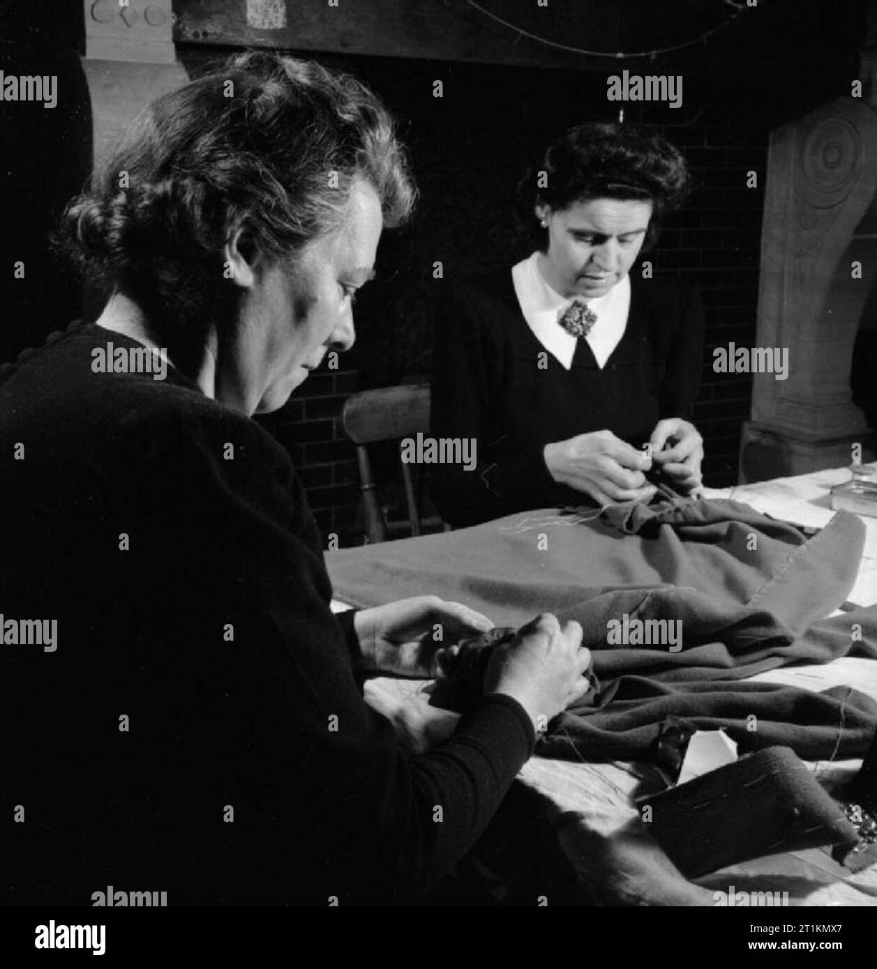 London Fashion Designer - die Arbeit der Mitglieder der Incorporated Society London Fashion Designer in Kriegszeiten, London, England, UK, 1944 In die arbeitsräume der Fashion Designer Norman Hartnell in London, zwei Mitarbeiter an einem Tisch und Tack zusammen einen Nachmittag Gehrock sitzen. Stockfoto