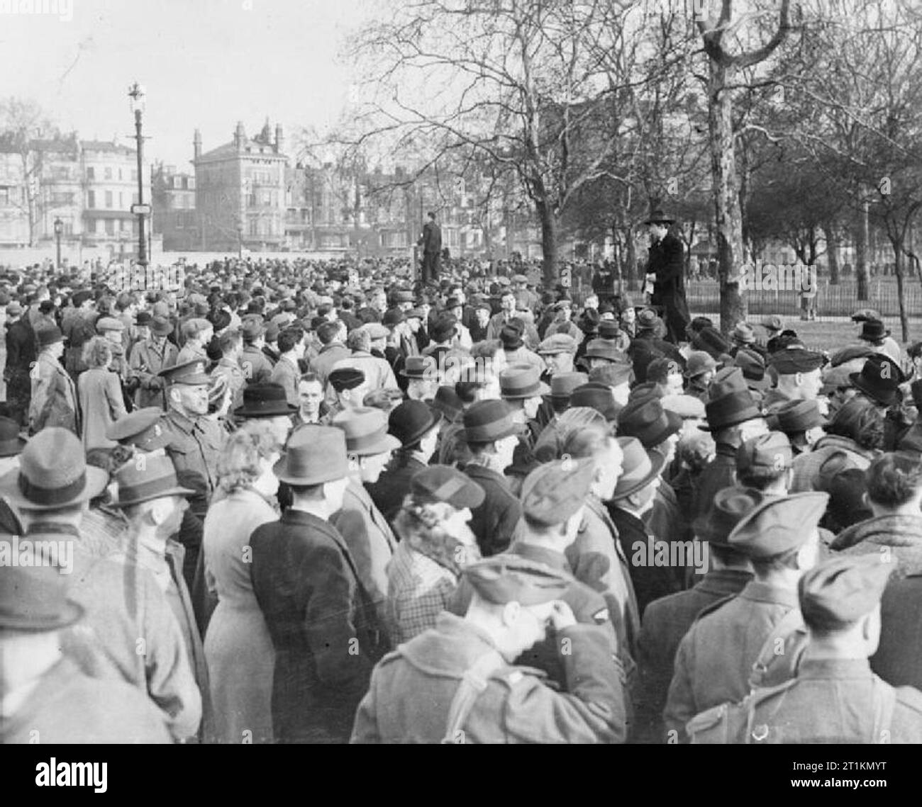 London im Frühjahr 1941 - Alltag in London, England eine grosse Menschenmenge in Speaker's Corner zusammengetragen hat, zu zwei der Referenten in Aktion hören unter den Bäumen am Rande des Hyde Park in London. Stockfoto