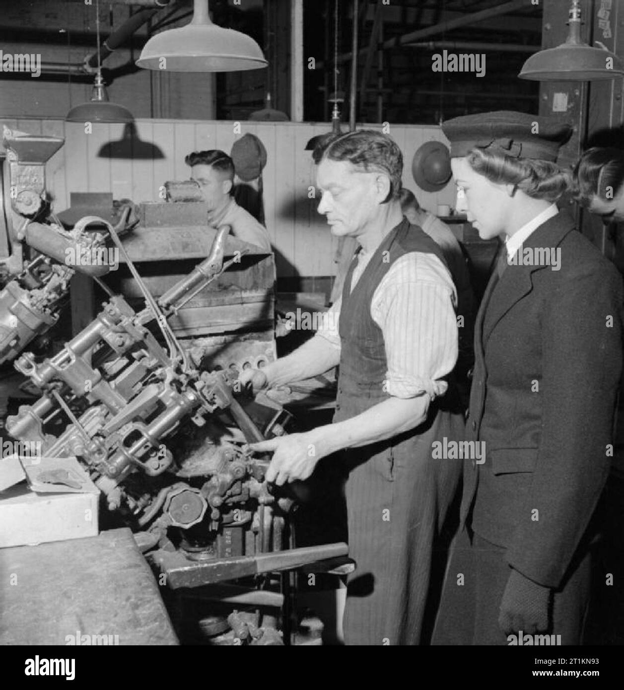 Herstellung von Schuhen für die zaunkönige - die Herstellung von Schuhen für die Women's Royal Naval Service bei einer Fabrik in den Midlands, England, Großbritannien, 1944 Mitglied der Royal Naval der Frauen Service Uhren ein Schuster bei der Arbeit auf einer großen Maschine, die die oberen in den letzten beimisst, nachdem der Innensohle haben angeheftet wurde. Dieser Prozess ist bekannt als "über" ziehen und bildet das Fundament für dauerhafte. Das letzte Modell der Schuhmacher für die Gestaltung der Schuh. Stockfoto