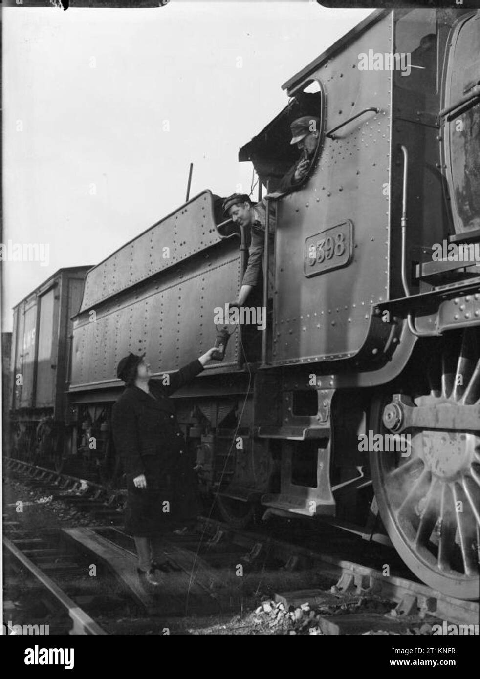 Naher Osten Sergeanten Frau Einweisende's Job-Leben Als Eisenbahn Signalwoman, Molland, Devon, England, UK, 1943 Signalwoman Daisy Kochen Hände eine 'token' ein Lokführer im Molland station in Devon. Die Ursprüngliche Bildunterschrift beschreibt die Systeme wie folgt: "Die 'token' ist eine Metallscheibe mit Namen auf. Es ist an den Treiber übergeben, bevor er die Station verlässt und muss an der nächsten Station übergeben werden, bevor ein Zug in die entgegengesetzte Richtung zu verlassen kann. Da es nur ein Token für jeden Abschnitt der Single Track, nur einen Zug gleichzeitig auf der Strecke sein können. Stockfoto