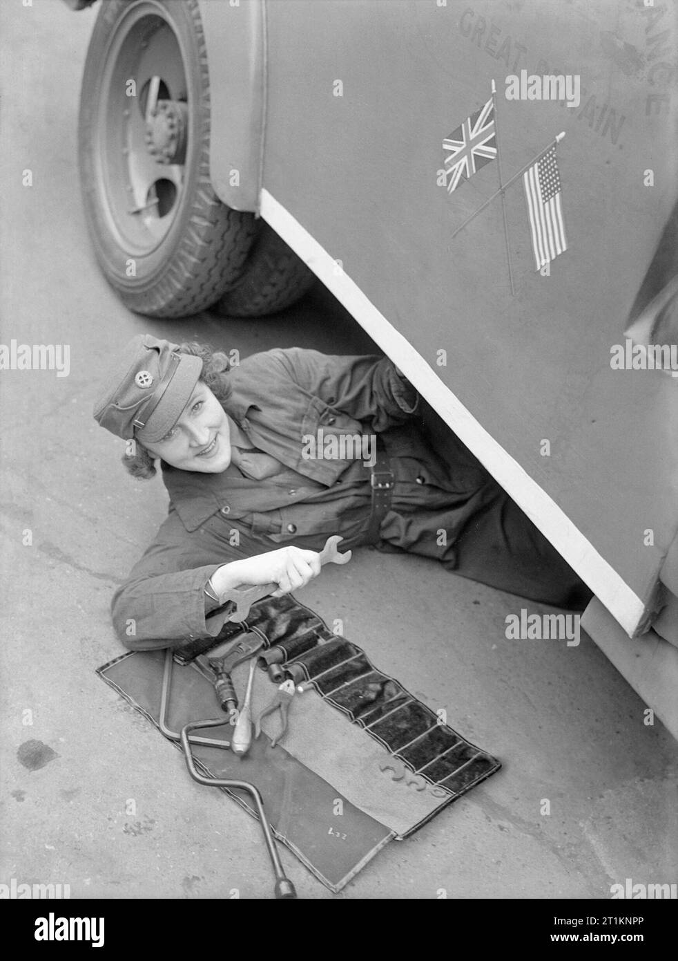 Mtc-Mädchen für Amerika - Frauen der mechanisierten Verkehrs Korps am Arbeitsplatz, London, England, 1940 Frau Pat Macleod Folien aus der Ambulanz ist sie Instandsetzung Lächeln für die Kamera an. Sie tut Wartungsarbeiten an Krankenwagen 8, die von Elliott Nugent Esq präsentiert wurde. Durch die American Field Service. Das Depot ist wahrscheinlich irgendwo in Paddington in London. Malte auf der Seite des Fahrzeugs sind die britische und amerikanische Flaggen, die zeigen, dass der Krankenwagen ist Teil der amerikanischen Krankenwagen, Großbritannien. Stockfoto