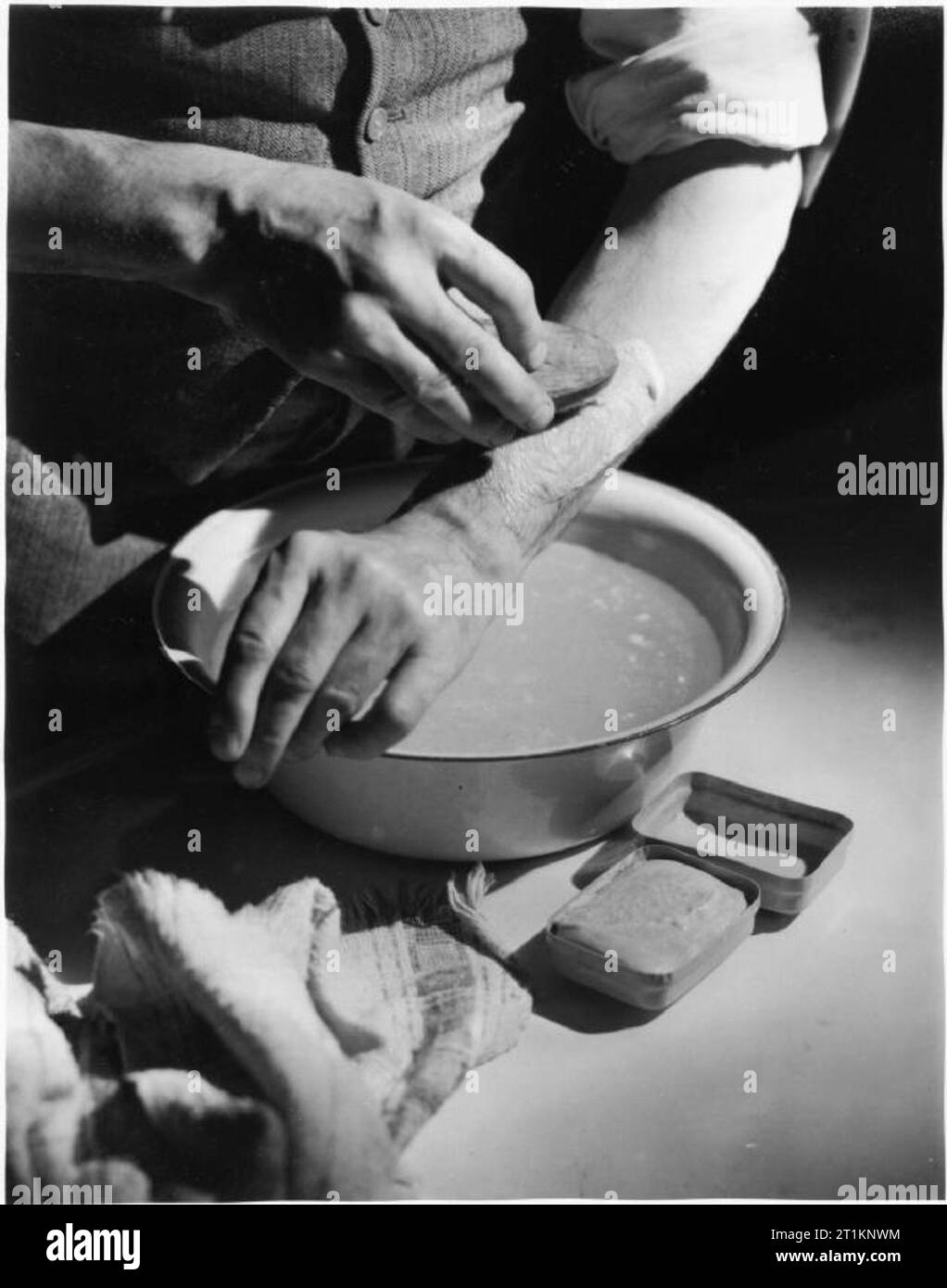 Air Raid Vorsichtsmaßnahmen auf dem britischen Home Front - Anti-gas Anweisung, C 1941 ein Mann gründlich wäscht seinen Arm, nachdem sie mit Flüssigkeit blister Gas spritzte. Er ist mit Wasser und Seife und Nagelbürste zu scheuern, entfernt alle verbleibenden gasteilchen. ARP-Richtlinien schlagen ändern das Wasser drei Mal während dieses Prozesses. Dieses Foto ist eindeutig durch ein Ministerium für Information Modell wurde für den Einsatz in irgendeiner Art von Prospekt, Ausstellung oder Poster. Stockfoto