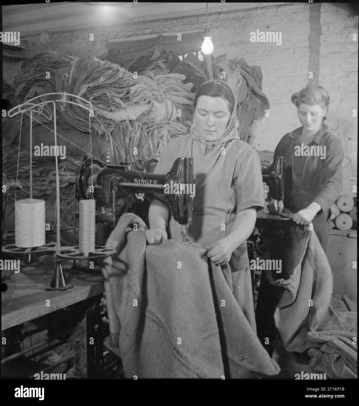 Neue Säcke für Alte - Bergung in Kriegszeiten Großbritannien, 1943 Frau Nancy Marchant betreibt einen Stopf Maschine in einen Sack Aufbereitungsanlage, irgendwo in London. Aufzeichnung von Frau Marchant Ausgabe 850 Taschen in einem Tag. Hinter ihr, auch bei der Arbeit an der Nähmaschine, ist Miss Jones. Riesige Haufen von Säcken können auf der linken Seite des Fotos zu sehen. Stockfoto