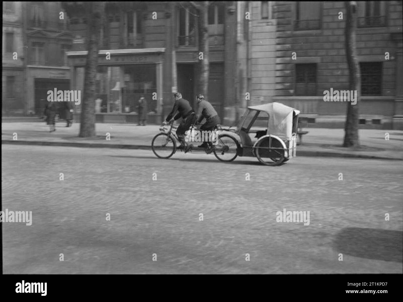 Paris, Spring 1945 - Alltag in Paris, Frankreich, 1945 ein 'Super Velo taxi" am Zielpfosten Kamera auf einer Straße in Paris, Frankreich. Dieses Velo Taxi hat zusätzliche Leistung, wie es 'Driven' von zwei Männern reiten ein Tandem. Die meisten Velo Taxis sind 'Driven' durch einen einzelnen Radfahrer auf einem normalen Fahrrad. Stockfoto