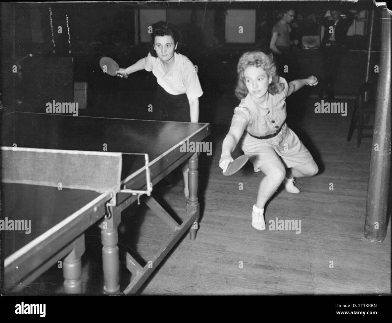 Bleiben Sie zu Hause Urlaub - Unterhaltung und Entspannung in Kriegszeiten London, England, 1943 Pinkie Barnes und Peggy Franks konkurrieren in einem Damen Doppel Tischtennis passen. Peggy hat nur eine geringe Rückhand zurück. Stockfoto