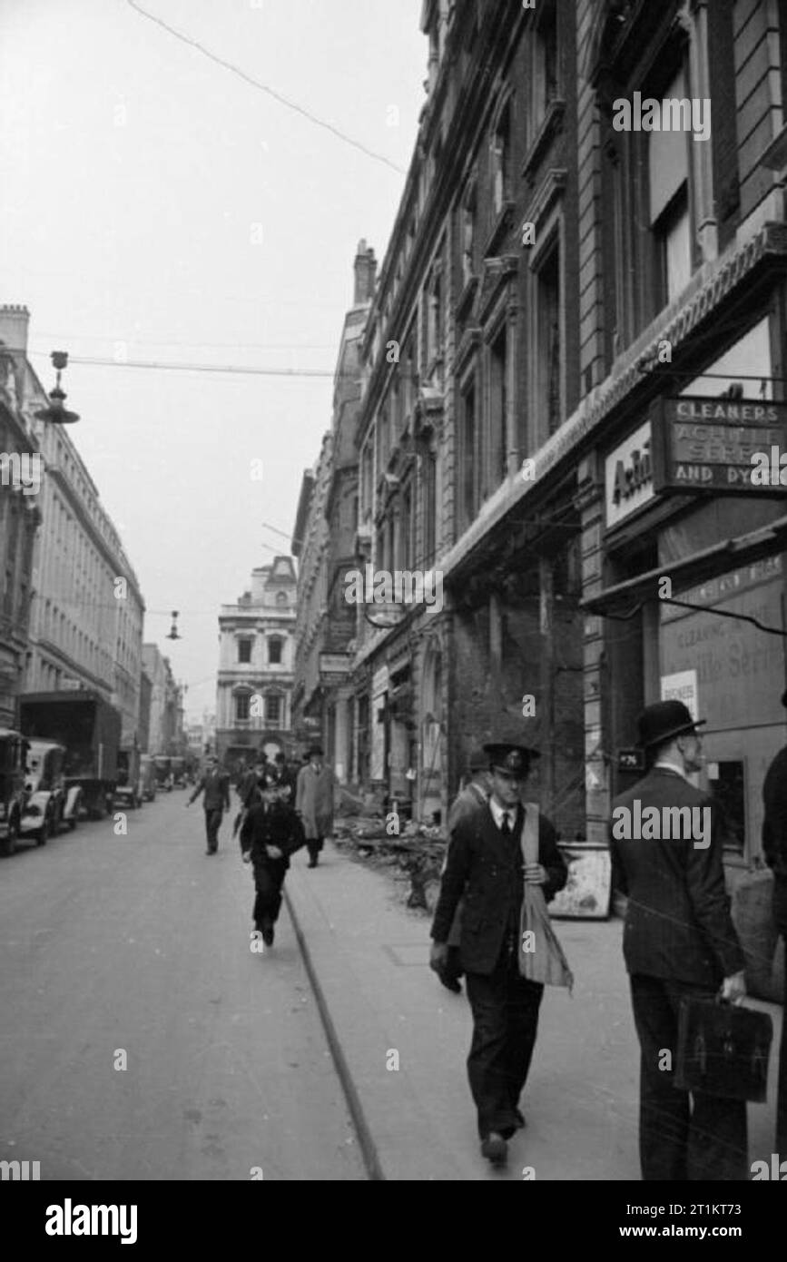 Das Telefon führt, London, Januar 1942 Ein messenger Boy (Mitte) nach unten läuft ein London Street, um die Nachricht durch die Mitarbeiter im Notfall Telefon Büro empfangen im Namen einer Telefon Teilnehmer, dessen eigene Telefon System durch einen Luftangriff beschädigt wurde. Im Vordergrund, ein briefträger gesehen werden kann. Der Shop auf der rechten Seite ist Achille Serre Reinigung, und im Hintergrund die Gebäude der Guildhall Versicherung und Atlas Qualitätssicherung gesehen werden kann. Eine kleine Menge von bombenschäden können auf der rechten Seite gesehen werden. Stockfoto