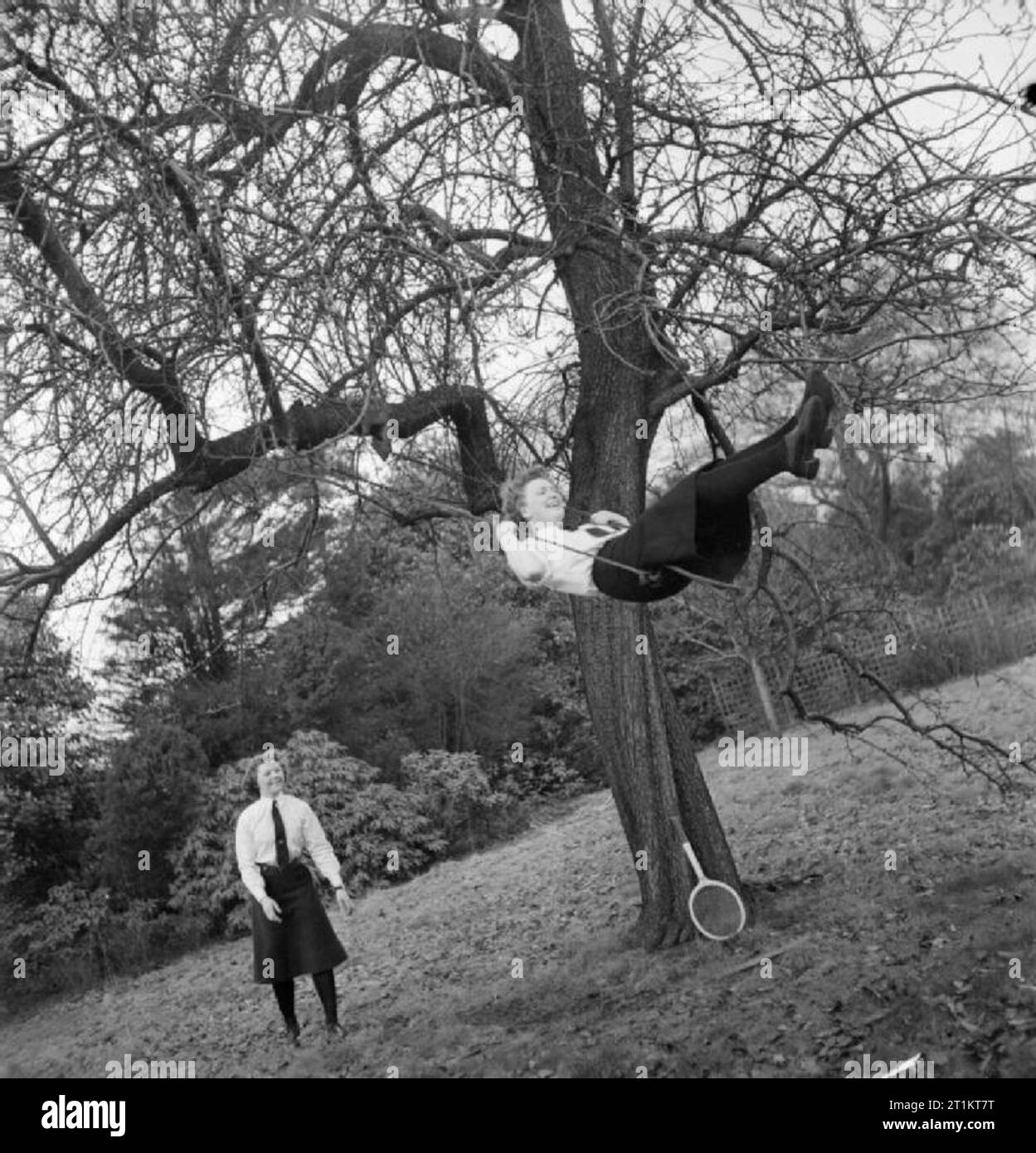 Das Unbekannte Mädchen hinter dem Meer Schlacht - die Arbeit von Women's Royal Naval Service, 1942 Wren Unbekannt genießt eine entspannende schwingen in einem großen Baum in der Nähe der HMS ADLER, wie ein weiteres Wren drücken Sie die Swing höher. Ein Tennisschläger kann auf der Basis der Struktur gesehen werden, was darauf hinweist, dass der Sport ist zweifellos wichtig, diesen Frauen, wenn aus Pflicht. Stockfoto