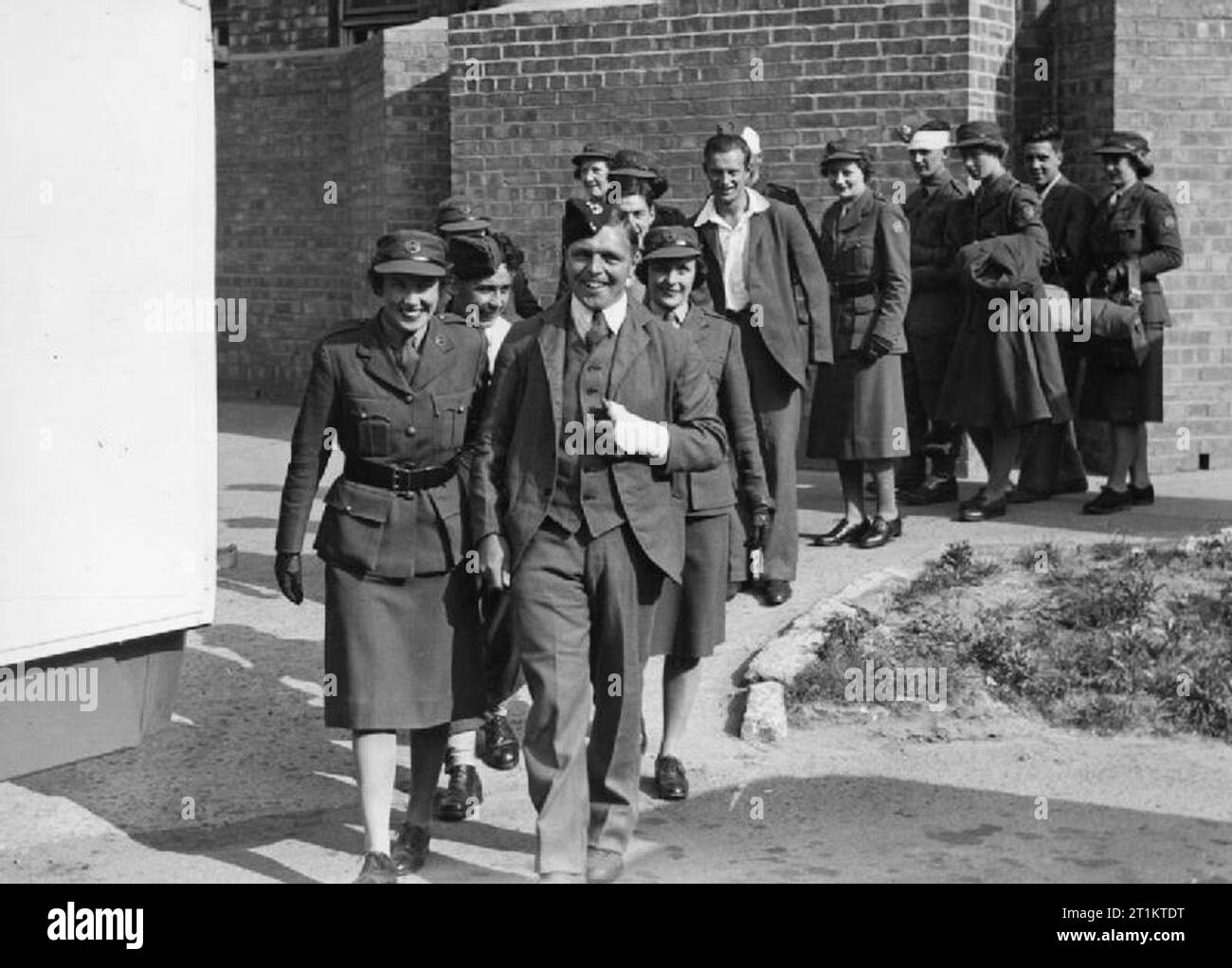 Die Arbeit der anglo-amerikanischen Sanitaetseinheit in Großbritannien, Frauen 1941 des anglo-amerikanischen Sanitaetseinheit führen zu Fuß Soldat Patienten Krankenwagen zu warten, da Sie von einem Krankenhaus zu einem anderen übertragen, irgendwo im Nordosten von England. Der Soldat hat einen bandagierten Hand, während andere Verbände auf ihren Köpfen. Stockfoto