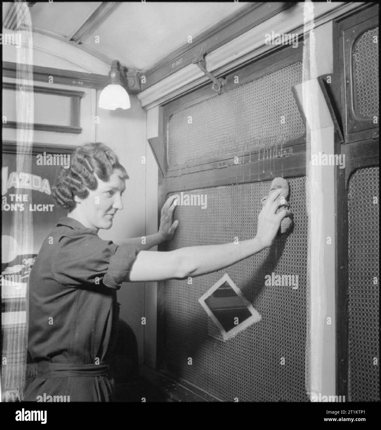 U-Bahn Frauen - Frauen bei der Arbeit auf dem Londoner U-Bahnnetzes, 1942 Frau Hilda Slater ein Fenster einer U-Bahn Station in London reinigt. Die Fenster sind mit Gitter abgedeckt worden - Verrechnung die Gefahren des Fliegens Glas in der Luftangriffe zu begrenzen. Ein Diamant-Bohrung in der gittererzeugung überlassen worden ist, so dass sich die Fahrgäste sehen kann, welche Station Sie sind. Stockfoto