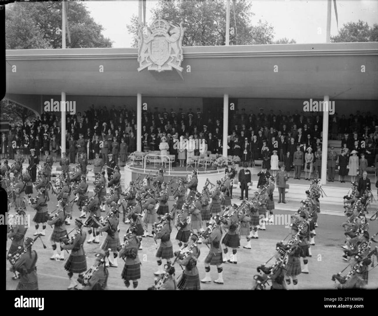 Sieg Parade in London, England, UK, 8. Juni 1946 Geballte pipers von Schottischen und Irischen regimentern März Vergangenheit der ehrenkompanie Basis in der Mall. Auf der Empore, von links nach rechts sind: Königin Elizabeth, HM König George VI, Prinzessin Elisabeth, Königin Mary, Prinzessin Margaret. Auf dem Boden, auf der rechten Seite der Empore sind: Clement Attlee, Winston Churchill, William MacKenzie King und General Smuts. Stockfoto