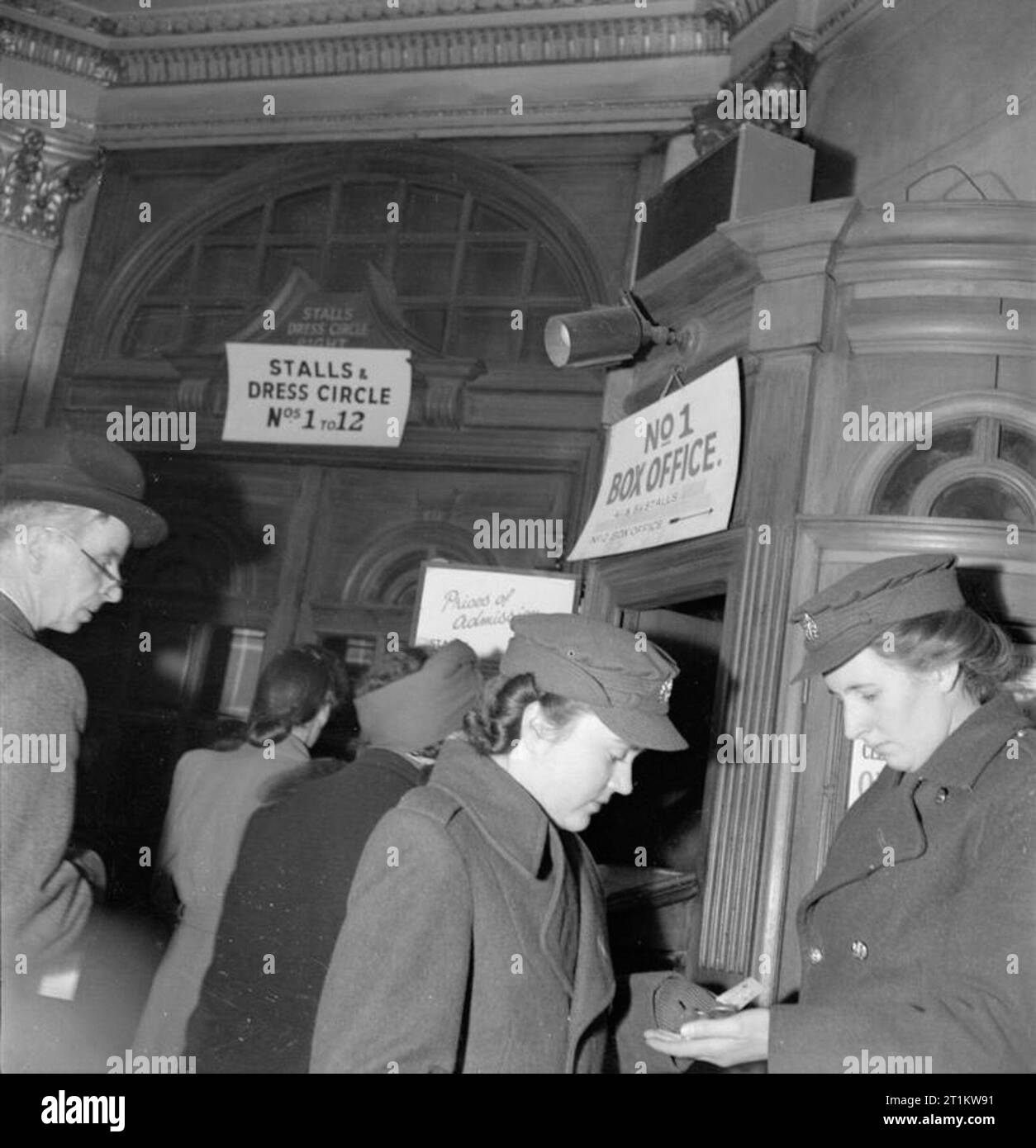 Kriegszeit Oper - Musik und Unterhaltung im Neuen Theater, St Martin's Lane, London, England, UK, 1943 Zwei Mitglieder des ATS ihre Änderung nach dem Kauf von Tickets an der Nr. 1 Box Office am Neuen Theater an der St. Martin's Lane in London. Hinter ihnen, Männer und Frauen queue Tickets zu kaufen. Ein Schild über der Tür weist auf die Stände und Dress Circle, Nummern 1 bis 12. Nach dem ursprünglichen Titel' die Opern sind so populär, dass es sehr schwierig ist, Sitze auf der Nacht der Leistung'. Stockfoto