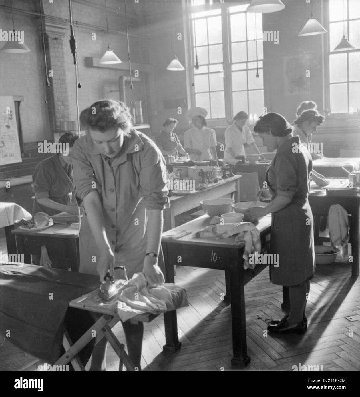 Ats Hauswirtschaft Kurs - Home Management Training, Notting Hill Gate, London, England, UK, 1944 Frauen der Auxiliary Territorial Service bei der Arbeit in der Küche von Avondale Park Schule in Notting Hill während ihres zweiwöchigen Kurs in der Hauswirtschaft. Bügeln im Vordergrund ist der 18 Jahre alte Private Sylvia Rendell, die nur in der ATS für sechs Wochen. Sie war eine Milchbar Assistant bevor er oben. Hinter ihr, andere Frauen Gebäck. Stockfoto