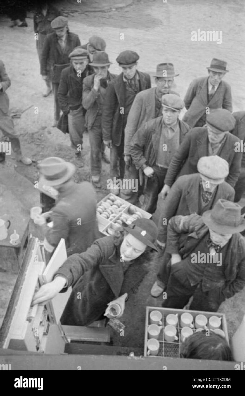 Blitz Kantine - Frauen der Frauen Freiwilligendienst einen mobilen Kantine in London, England, 1941 Geduld "Buh" Marke in einem Fach im WVS Kaffee Auto erreicht eine Packung Zigaretten für einen der Männer queuing Kaffee zu kaufen, Brötchen, irgendwo in London, 1941. Diese Männer waren zuvor arbeitslos, aber jetzt arbeiten zu löschen Schutt und Trümmer durch einen Luftangriff zu diesem Bereich verursacht. Stockfoto
