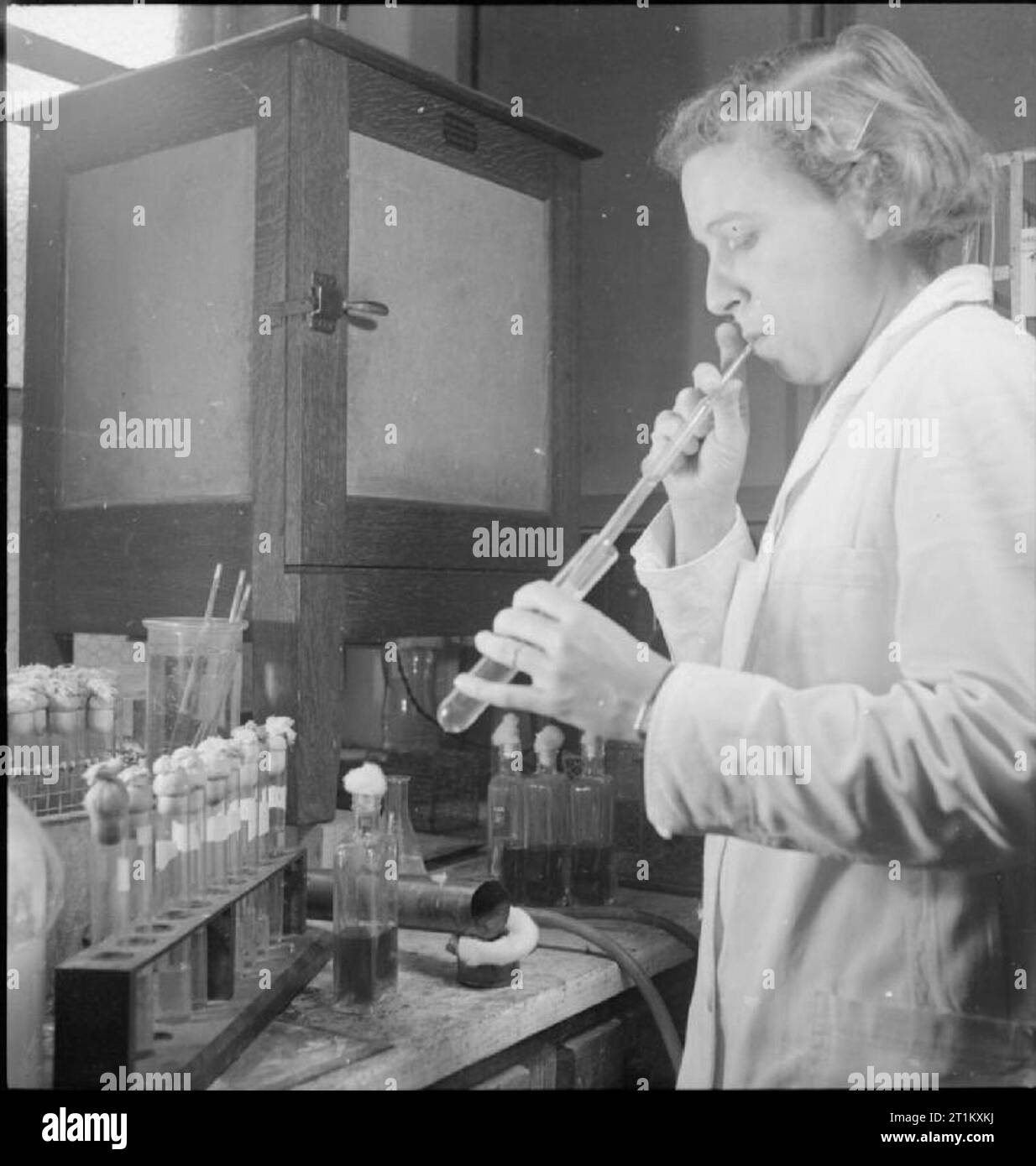 Blut Trocknen - Verarbeitung von Blut im Labor, Cambridge, England, UK, 1943 Mitarbeiter am Blut trocknen Einheit an der Cambridge Universität zieht Steril, gefiltert, Plasma von Röhrchen in die Transfusion Flaschen. Sie ist mit einer Pipette - Typ Apparatur die Flüssigkeit mit Ihrem Mund in die Pipette zu saugen das Plasma in die Flaschen zu übertragen. Stockfoto