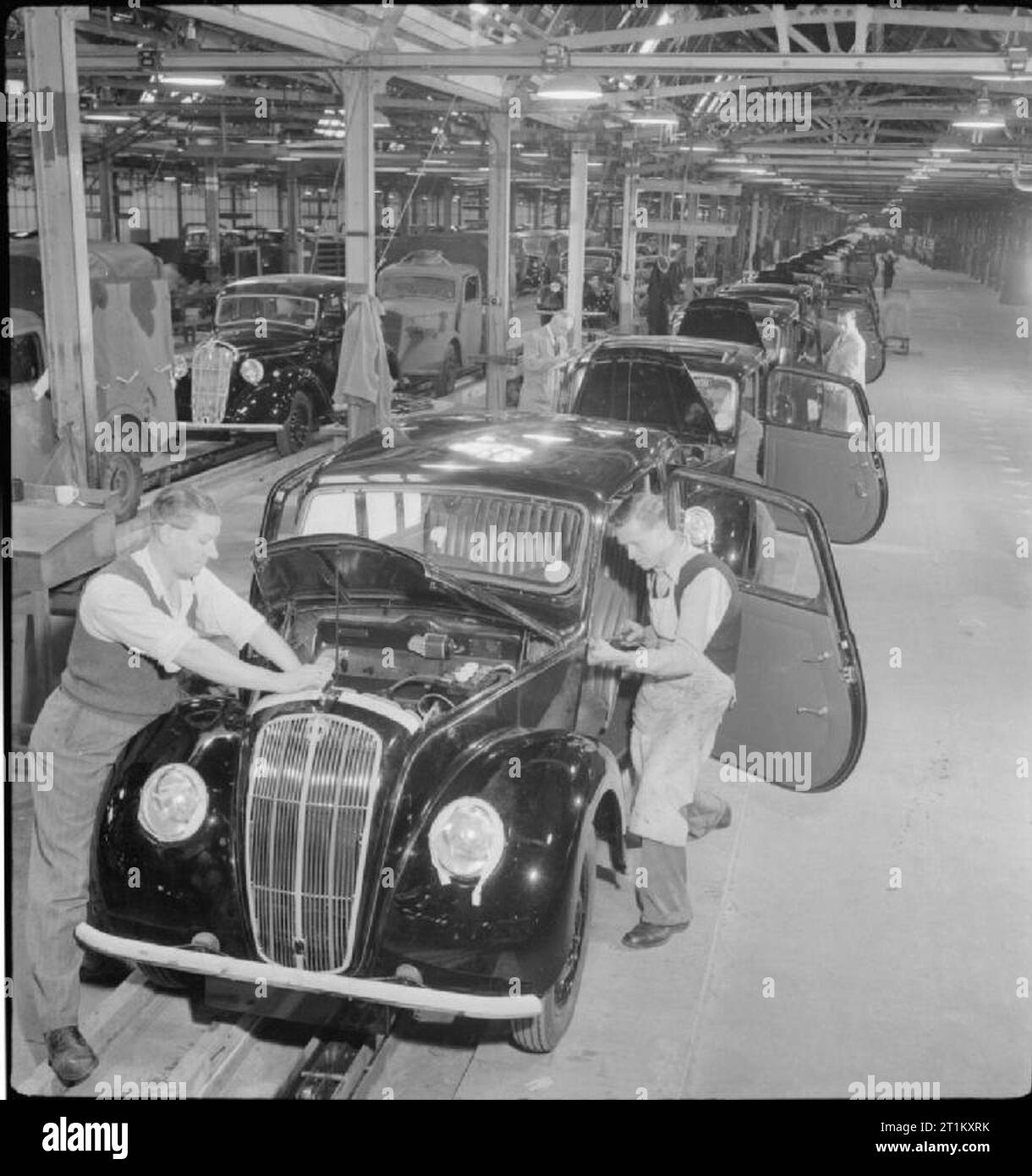 Großbritannien baut Leichte Autos - die britische Automobilindustrie, UK, 1945 Arbeiter hinzufügen letzte Hand an ein Auto auf dem Fließband einer Autofabrik, irgendwo in Großbritannien. Der Workshop ist riesig, und Autos zu sehen, die bis in die Ferne, so weit das Auge sehen kann. Stockfoto