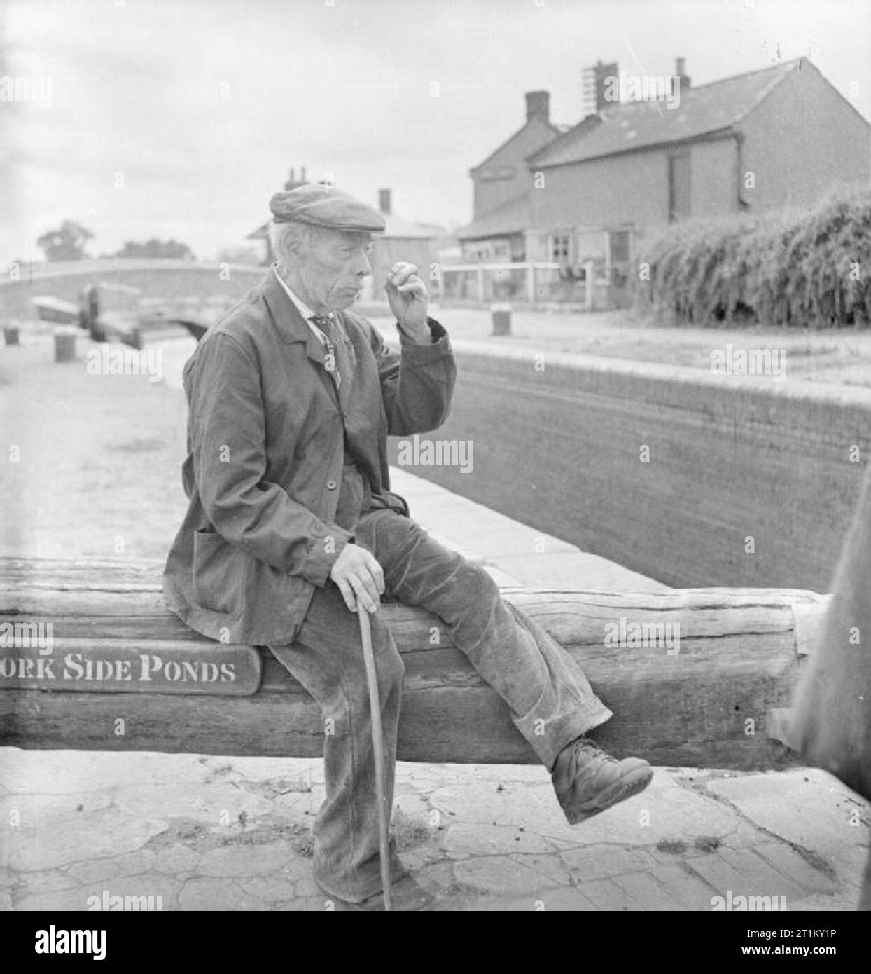 Britische Kanäle in Kriegszeiten - Verkehr in Großbritannien, 1944 Rentner Jim Beam Pritty auf eine Sperre sitzt bei Long Buckby auf dem Grand Union Canal in Northamptonshire. Gemäß der ursprünglichen Bildunterschrift, Jim war ein Segler, in den Tagen der Pferdekutschen- boote und verbringt jetzt seine Zeit mit der Vorbereitung der Schlösser für die Schiffer, kurz sind - übergeben, für einen Groschen. Die Worte "ide-Teiche' kann man auf den Strahl gesehen werden: Seite Teiche wurden als eine Möglichkeit der Einsparung von Wasser rund um die Schlösser integriert. Stockfoto