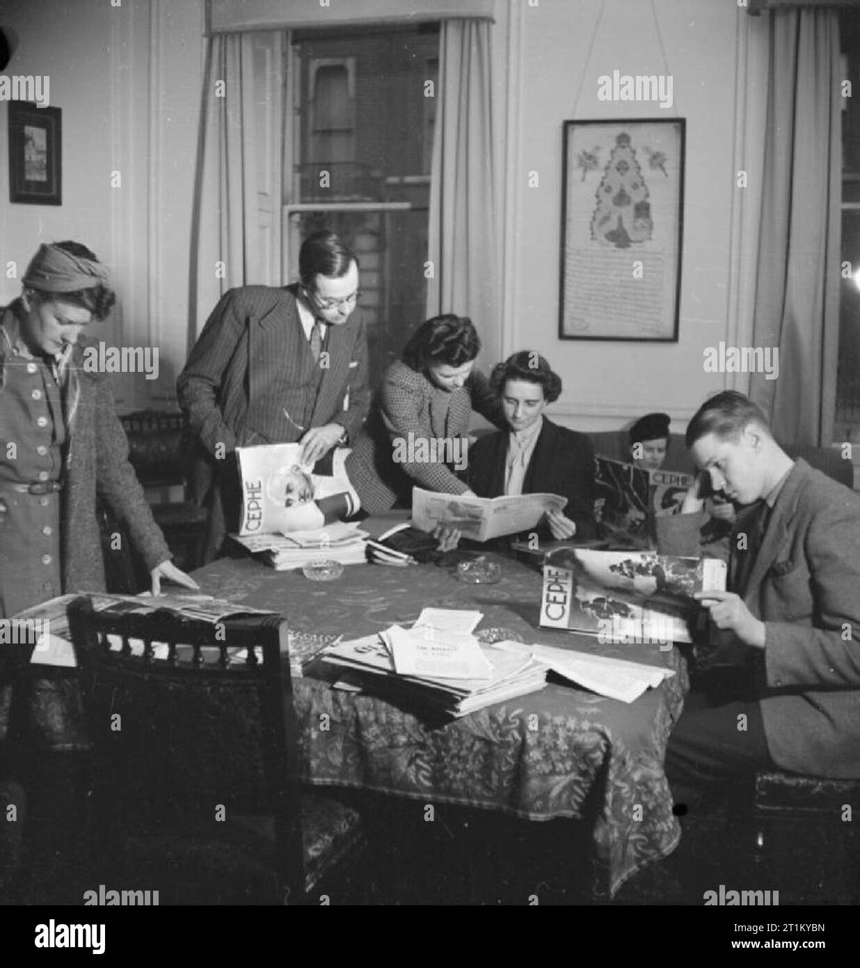 Briten lernen Türkisch - Erwachsenenbildung in London lasen 1943 britische Associate Mitglieder der Londra Turk Halkevi Kopien der türkischen Zeitschrift Cephe, um ihnen beim Studium der Sprache zu helfen. Von links nach rechts sind sie: Miss Blundell, Mr. J P Hardy, Miss Nora Bagguley, Miss K Griffin und Mr. Alistair Goldsworthy. Die meisten lernen Türkisch aus geschäftlichen Gründen. Hinter ihnen an der Mauer befindet sich ein altes Kaiserdekret, geschrieben in altrarabischer Schrift. Es wurde den Halkevi von Sultan Mahmut.Türkce präsentiert: ?Ngilizler Türkce Ö?reniyor - Londra'da Yeti?kin E?itimi, 1943Londra Türk Halkevi'nin?ngiliz Yard?mc? Üy Stockfoto