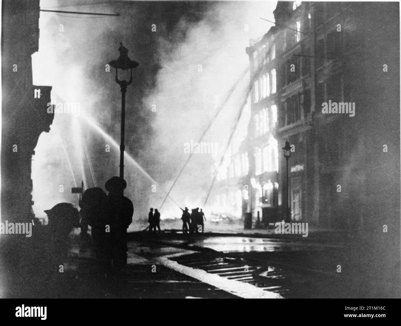 Der zweite Weltkrieg 1939 - 1945 - Home Front Mitglieder der Londoner Feuerwehr Zug ihre Schläuche auf brennenden Gebäuden im Queen Victoria Street, EC4, nach dem letzten und schwersten großen Raid auf die Hauptstadt während der 'Blitz' montiert. Für sechs Stunden in der Nacht des 10./11. Mai 1941, Flugzeuge der Luftwaffe fielen über 1.000 Tonnen Bomben auf London, behauptet 1.486 Leben, 11.000 Häuser zerstört und beschädigt, einige der wichtigsten historischen Gebäude, darunter die Häuser des Parlaments, das British Museum und die St. James's Palace. Die Ebbe und mehr als 40 gebrochene Netz beraubt das Feuer Stockfoto