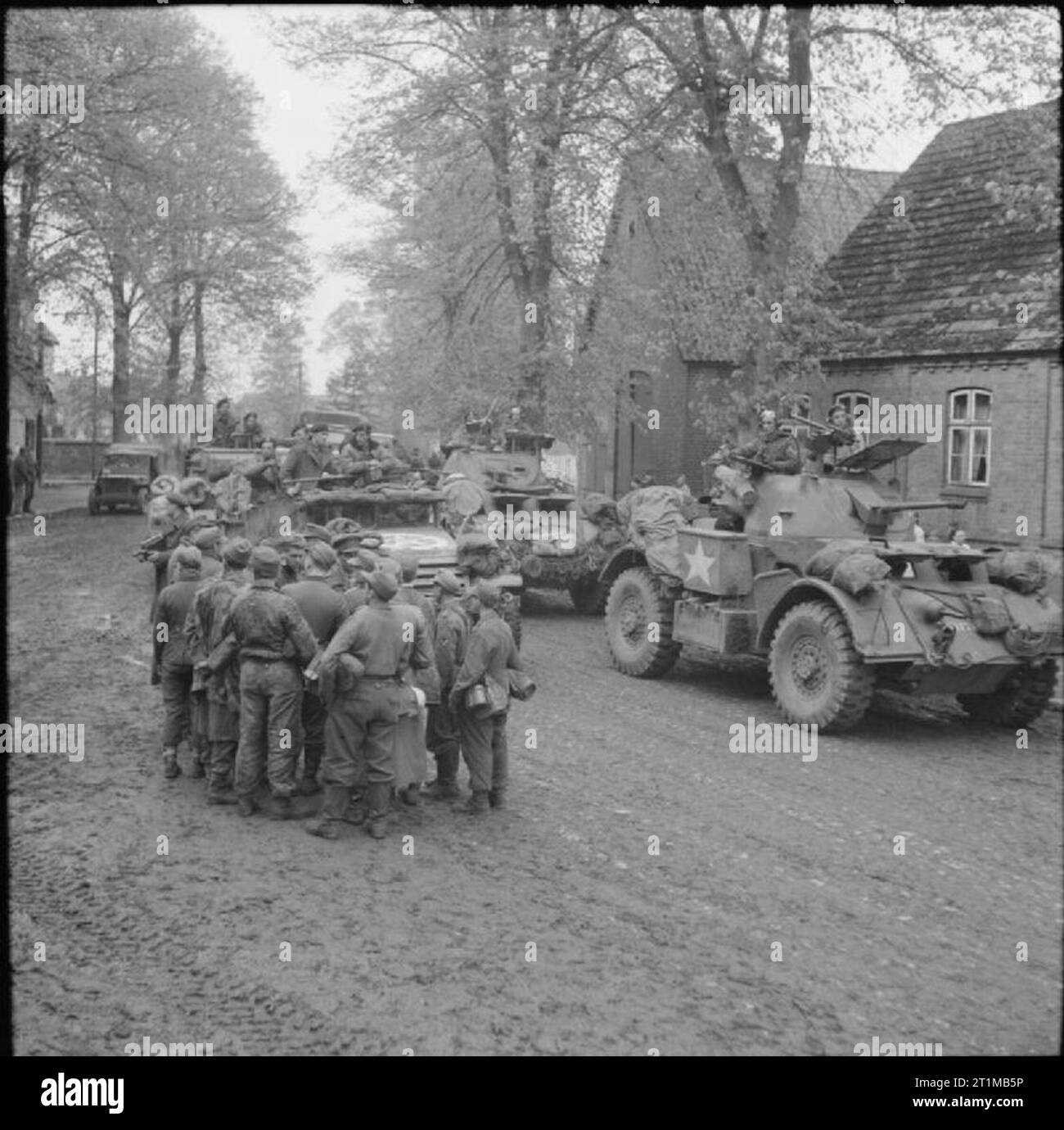 Die britische Armee in Nord-West-Europa 1944-45 Staghound gepanzerte Fahrzeuge und Halbkettenfahrzeugen pass deutsche Kriegsgefangene in Gudow, 2. Mai 1945. Stockfoto