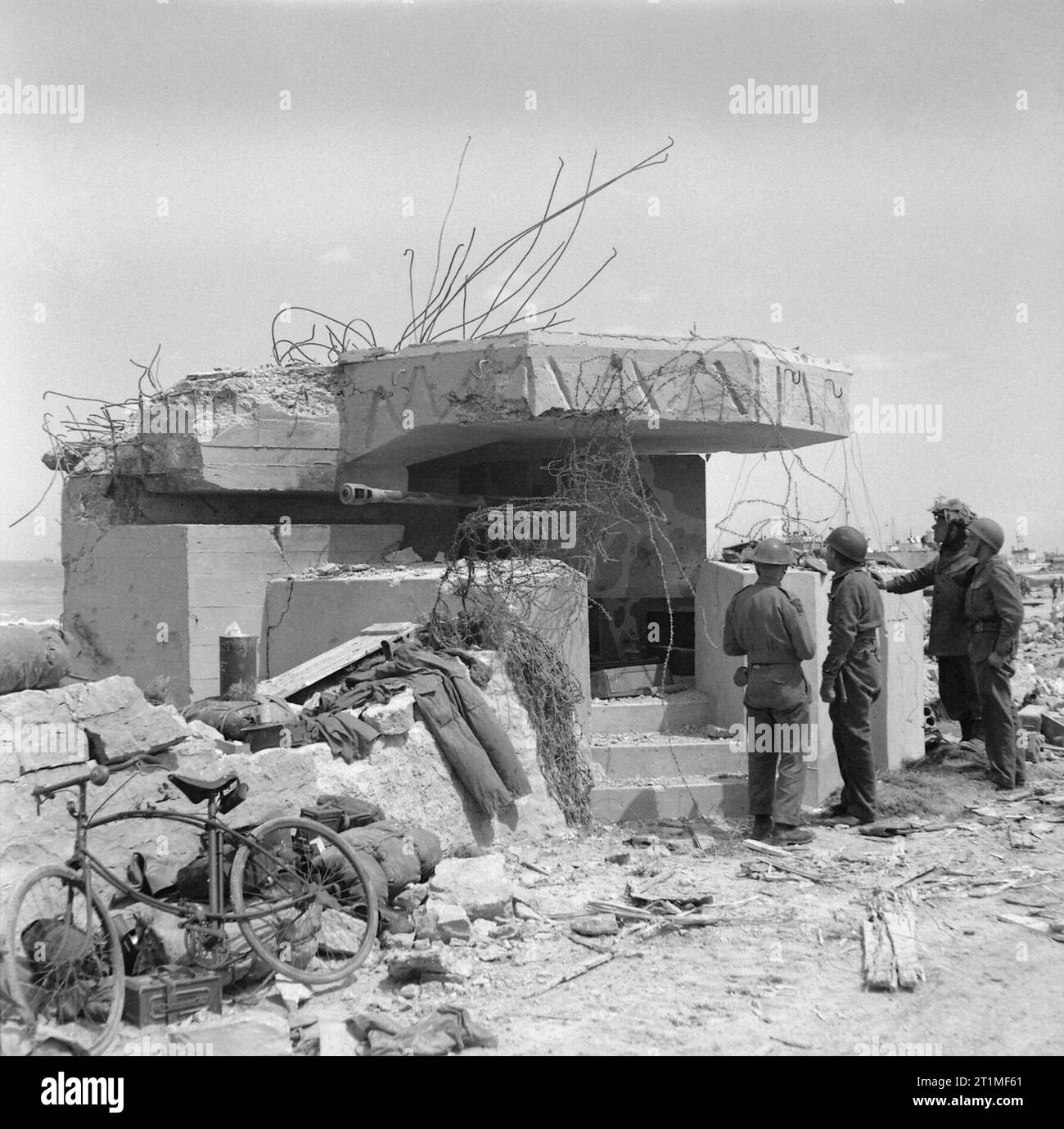 Die Invasion der Normandie 1944 Truppen inspizieren ein ausgehöhtes deutsches 50mm Gewehr (5 cm Kampfwagenkanone 39/1) in seiner Stellung am Gold Beach. Stockfoto