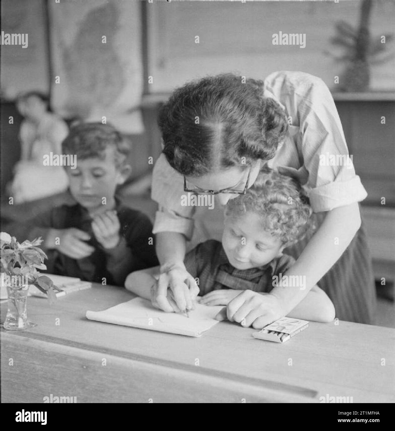 Die Befreiung der Konzentrationslager Bergen Belsen, Juni 1945 Kindern wird beigebracht, in der Schule, die in das Lager nach der Befreiung geöffnet zu schreiben. Die Kinder, die aus Polen, der Tschechoslowakei und Ungarn kamen, sind von Irene Mandel, eine tschechische Schule Lehrer, der im Lager interniert wurde gelehrt. Miss Mandel spricht fünf Sprachen, sondern lehrte in deutscher Sprache, die einzige Sprache, die alle Kinder verstanden. Stockfoto