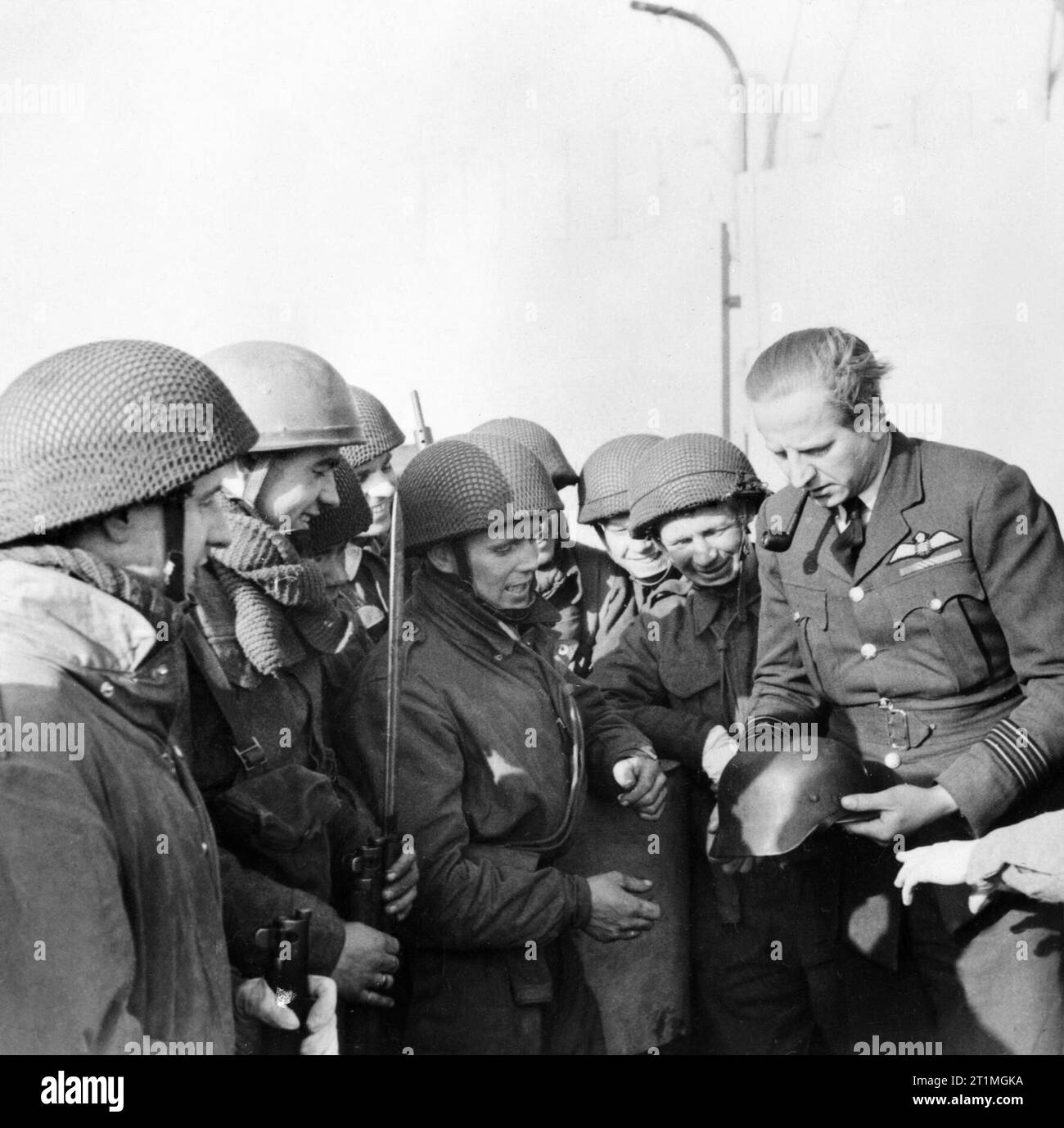 Wing Commander Percy Pickard, CO von Nr. 51 Squadron RAF, inspiziert einen gefangengenommenen deutschen Helm mit Truppen aus 2 Fallschirm Bataillon nach dem Bruneval raid, 28. Februar 1942. Squadron Leader Percy Pickard, Kommandierender Offizier der Nr. 51 Squadron RAF, inspiziert einen gefangengenommenen deutschen Helm mit Fallschirm Truppen nach dem Bruneval raid, 28. Februar 1942. In der Nacht vom 27./28. Februar Pickard's Geschwader von Whitleys fallengelassen 'C' Unternehmen, 2 Fallschirm Bataillon (unter dem Kommando von Major J D Frost) in der Nähe von Deutschen Würzburg radar site an Bruneval in der Nähe von Le Havre in Frankreich - Ziel Komponenten zu ergreifen Stockfoto