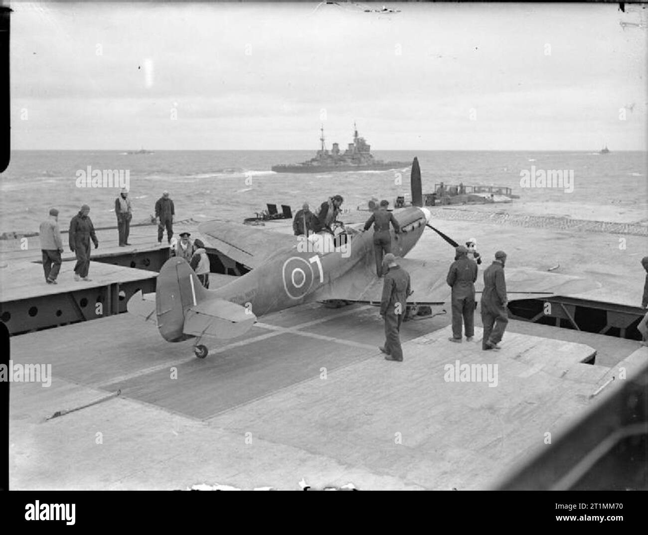 Die Royal Navy während des Zweiten Weltkriegs ein Supermarine Seafire von 801 Squadron, Fleet Air Arm an Bord der HMS FURIOUS mit dem Piloten noch im Cockpit, ist auf dem Weg zum Hangar nach der Rückkehr von patrouille während einer nördlichen Alliierten Konvoi. HMS DUKE OF YORK gesehen werden kann Segeln in der Mitte. Stockfoto