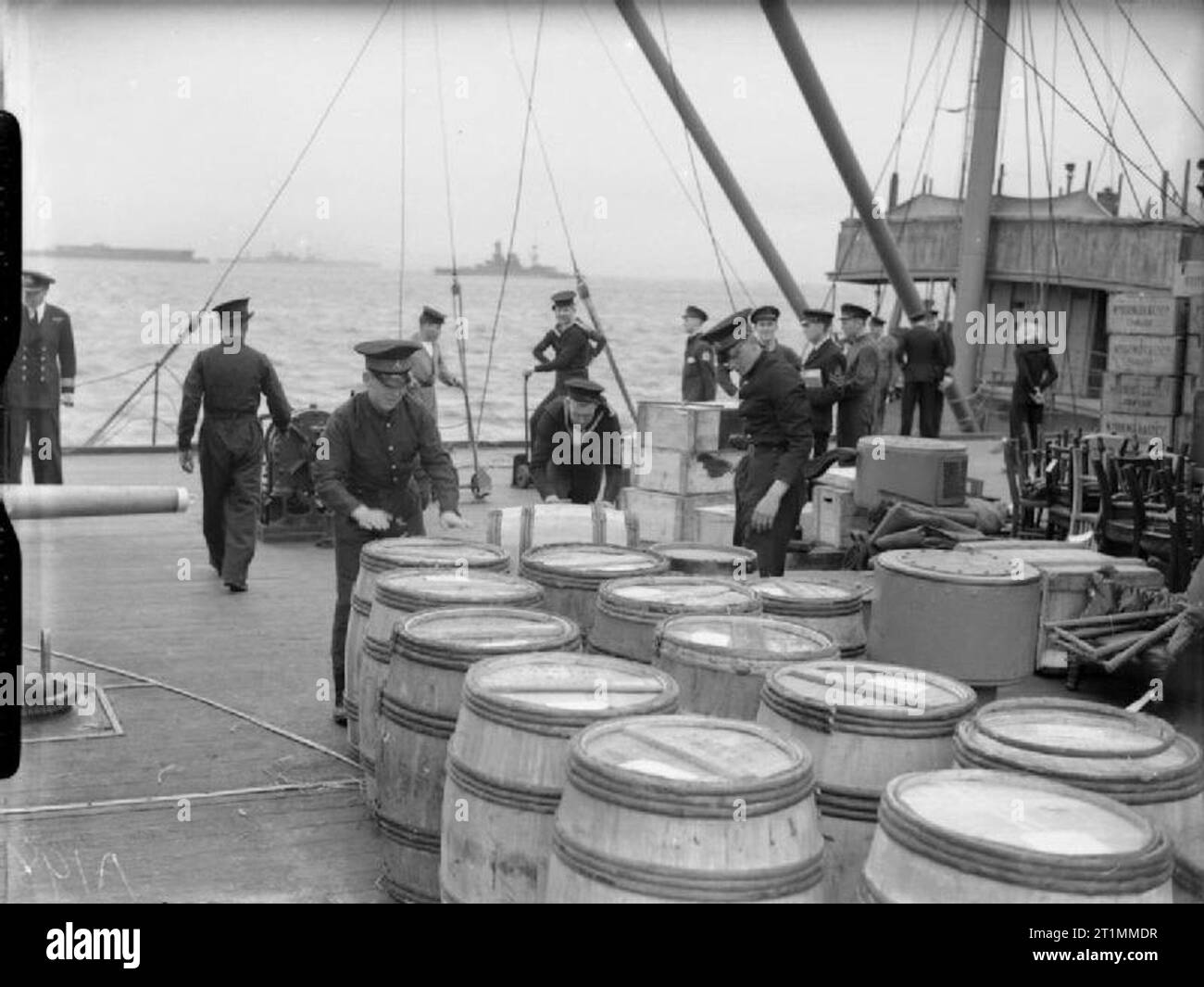 Die Royal Navy während des Zweiten Weltkrieges die Bereitstellung eines NELSON klasse Schlachtschiff, wahrscheinlich HMS Rodney und Vorräte für drei Monate. Royal Marines prüfen Sie die speichert, wie sie an Bord gebracht werden. Die Fässer enthalten Geschirr. Die Brücke des Schiffes kann im Hintergrund gesehen werden. Das Schlachtschiff durchgeführt eine Crew von über 1300. Stockfoto