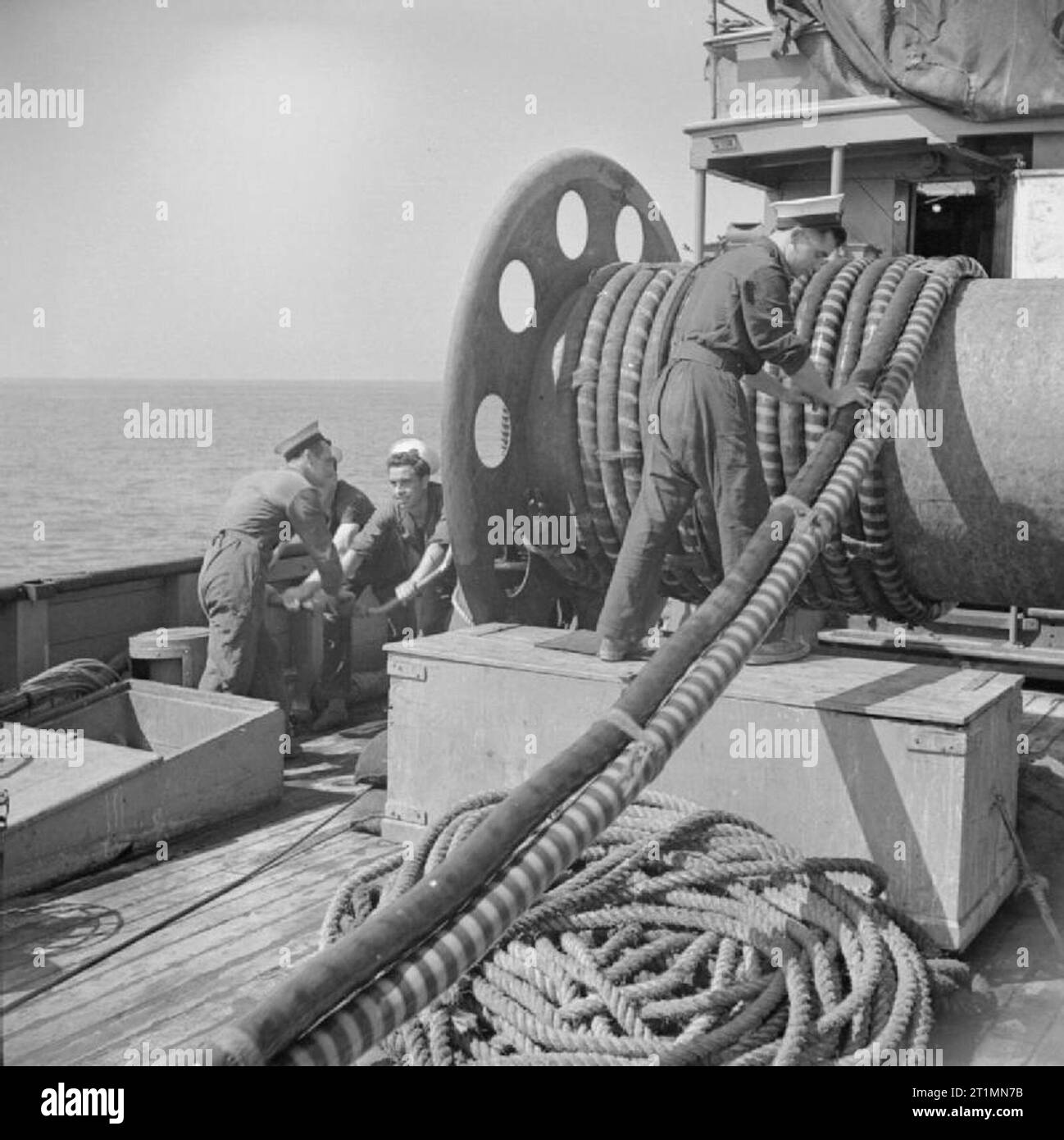 Die Royal Navy während des Zweiten Weltkriegs an Bord HM Motor Minesweeper 88 Während minesweeping Operationen aus Anzio, Italien. Von der Reihenfolge der "Sweeps", die Schleife ist in der Hand von den Matrosen auf der linken und auf eine große Trommel, wieder von Hand gewickelt. Stockfoto