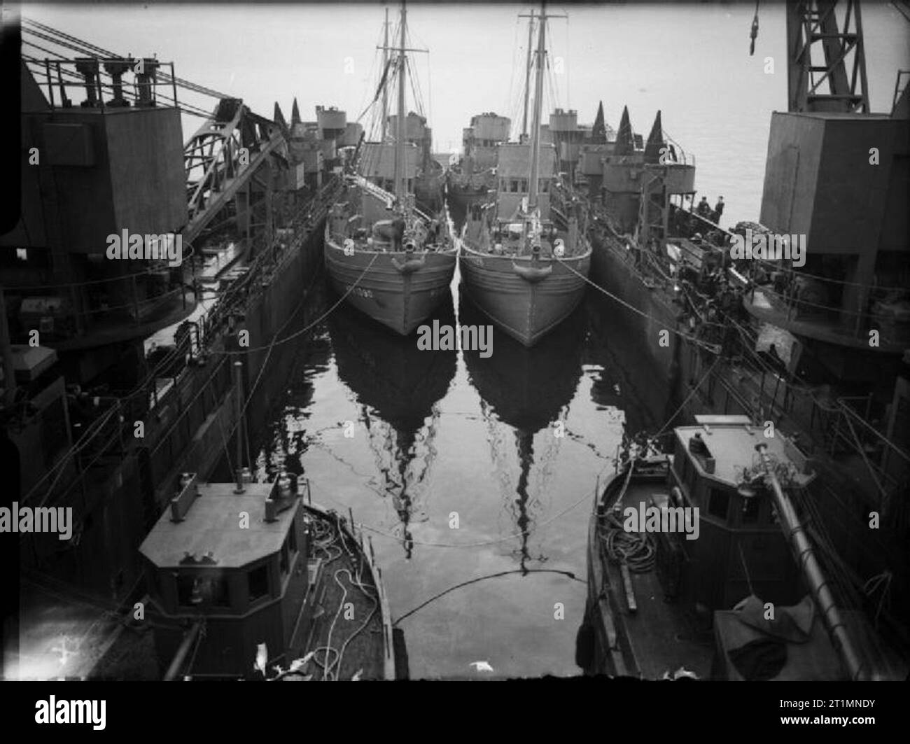 Die Royal Navy während des Zweiten Weltkrieges vier Motor Fischereifahrzeuge (MFV 1080 und MFV 1028 vor) gebunden in den überschwemmten Dock von HMS EASTWAY. Die Rampe ist, bereit für die Station entleert werden. Das Foto wurde aufgenommen, während der Landung Schiff Dock wurde der Weg von der Küste von Greenock. Stockfoto