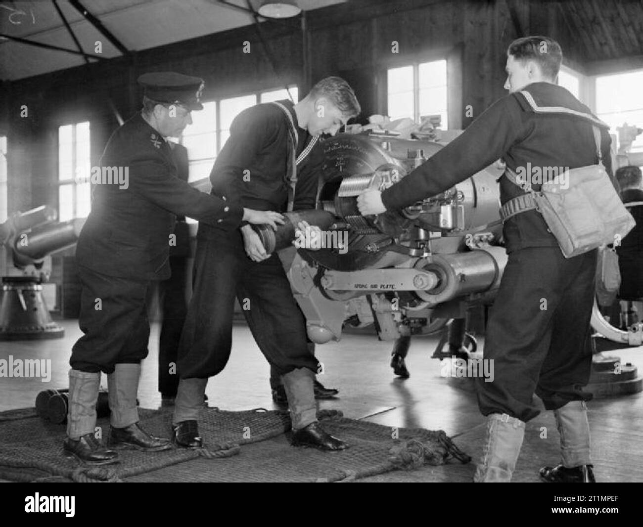 Die Royal Navy während des Zweiten Weltkriegs an HMS RALEIGH, die Naval training Basis in Yarmouth, Cornwall, neue Rekruten für die Marine laden das Projektil in den Hinterteil der 6 inch Gun. Die Waffe ist in einem großen Raum. Dieses Foto ist aus einer Serie von Bildern an die Fortschritte der einen Mann (John Smith) Eintritt in die Royal Navy und gehen durch Training genommen. John Smith war offensichtlich dankbar für die körperliche Ausbildung, das Anheben der schweren Schalen möglich für ihn. Stockfoto