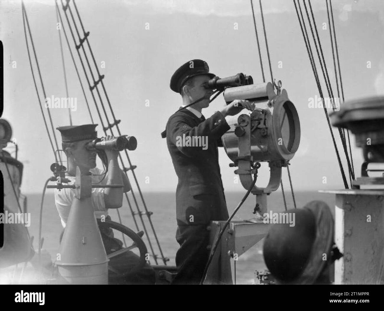 Die Royal Navy während des Zweiten Weltkrieges durch ein Fernglas, einem Mitglied der Schiffsbesatzung ist ein Signal für eine Verfolgung Schiff mit einer Signalleuchte an Bord der HMS brach während Sie auf See ist. Stockfoto
