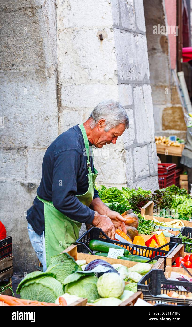 Ein lokaler französischer Stallhalter bereitet seine Produkte an einem Gemüsestand auf dem lokalen Lebensmittelmarkt in der Altstadt von Annecy, Frankreich, zu Stockfoto