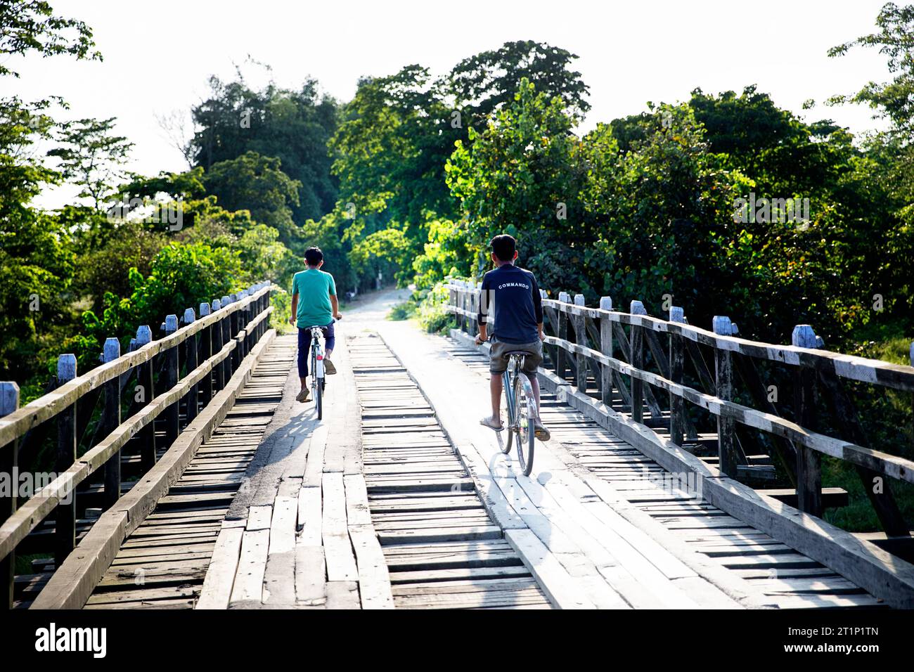 Zwei Teenager auf Fahrrädern überqueren an einem schönen sonnigen Sommertag die alte Holzbrücke auf der Insel Majuli in assam, indien Stockfoto