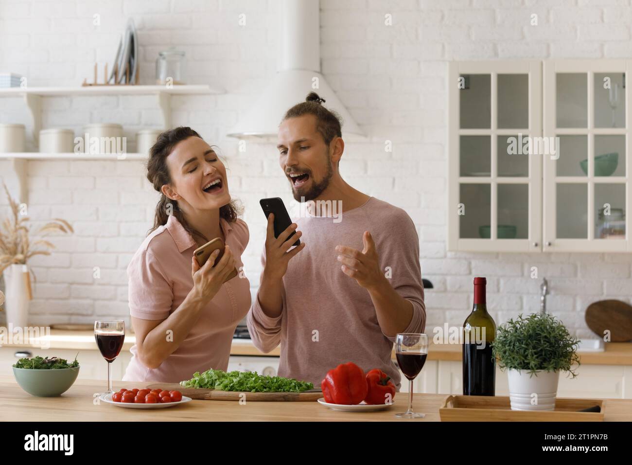 Glückliches Paar begeistert mit Liedern beim Kochen in der Küche Stockfoto