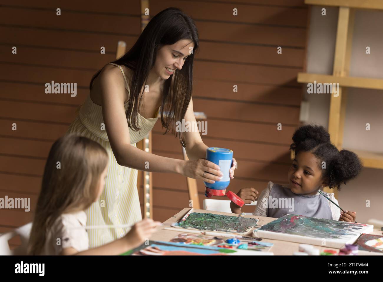 Kunstlehrer bringen kleinen Kindern das Malen bei Stockfoto