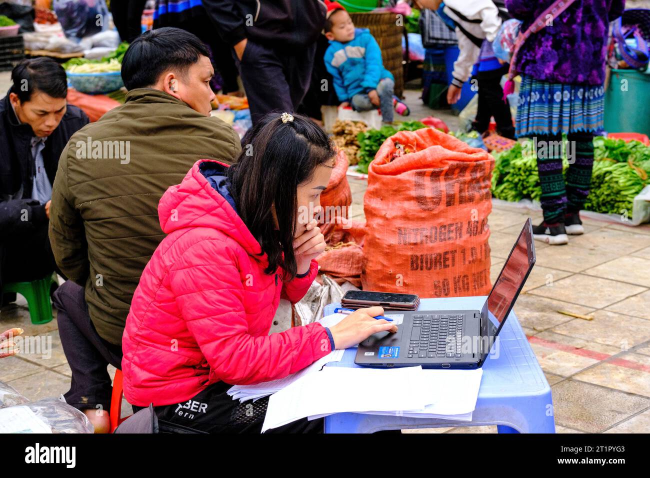 Bac Ha, Vietnam. Sonntagsmarktszene, junge Frau, die an einem Laptop arbeitet. Provinz Lao Cai. Stockfoto