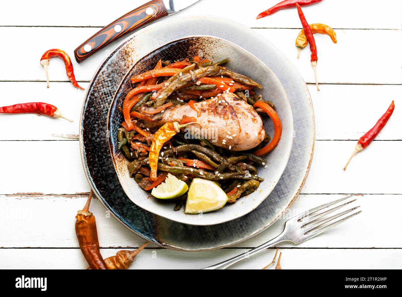 Gebratenes Hähnchen mit Gemüsegarnierung und Gewürzen. Geschmorte, würzige Hähnchenschenkel. Stockfoto