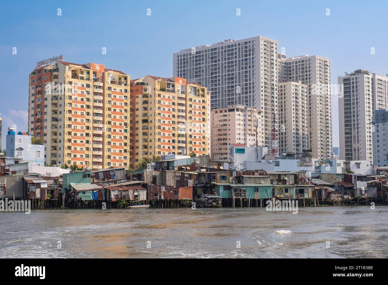 Ho Chi Minh, Vietnam. Nebeneinander von Hochhauswohnungen und armen Wohnhäusern am Fluss Saigon. Stockfoto