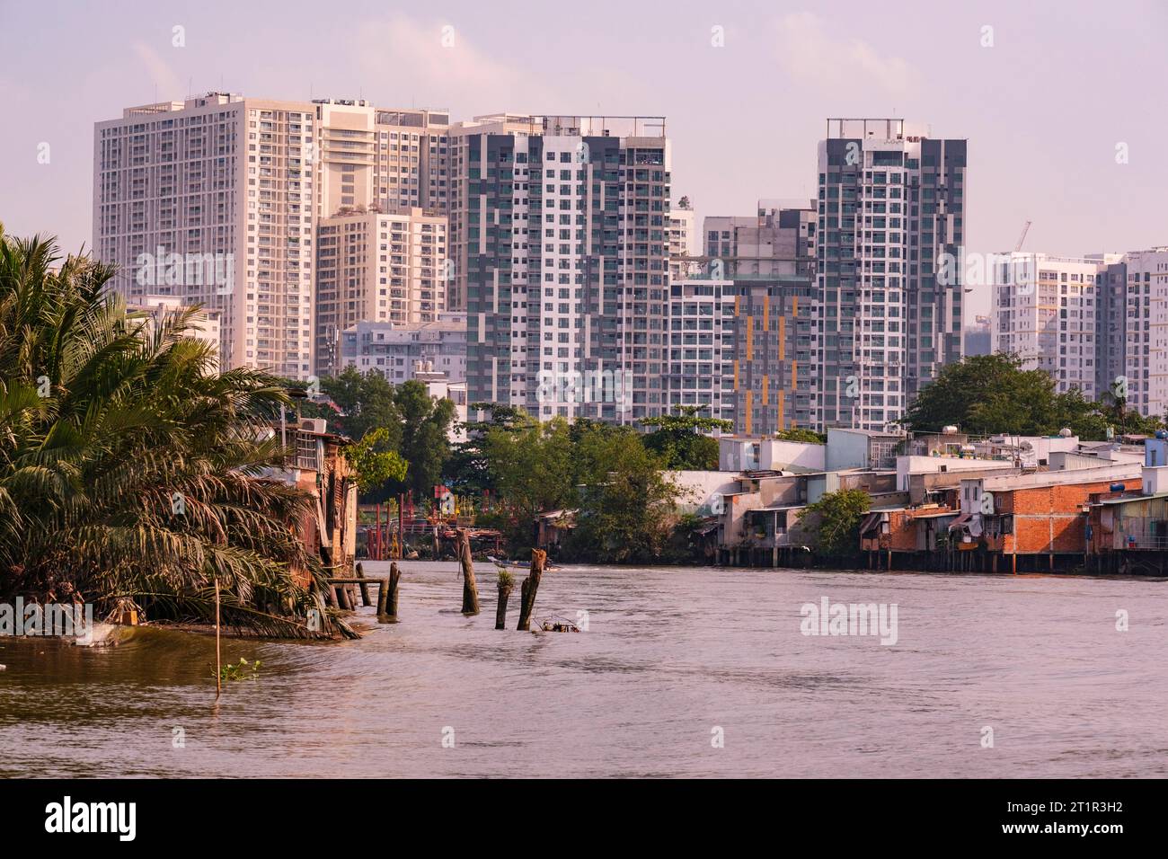 Saigon Riverside View in der Nähe von Ho Chi Minh, Vietnam. Gegenüberstellung von modernen Hochhauswohnungen mit bescheidenen Wohnhäusern der unteren Klasse. Stockfoto