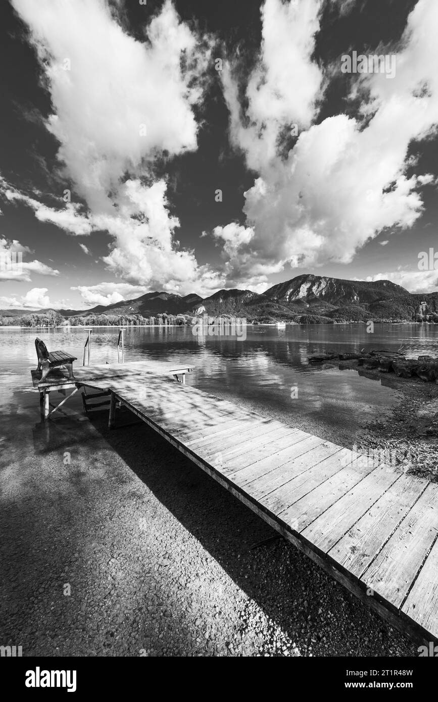 Wolken, die über eine hölzerne Fußgängerbrücke am Ufer des Kochelsees vor herbstlicher Berglandschaft treiben und Wolken am Himmel, Bayern Stockfoto