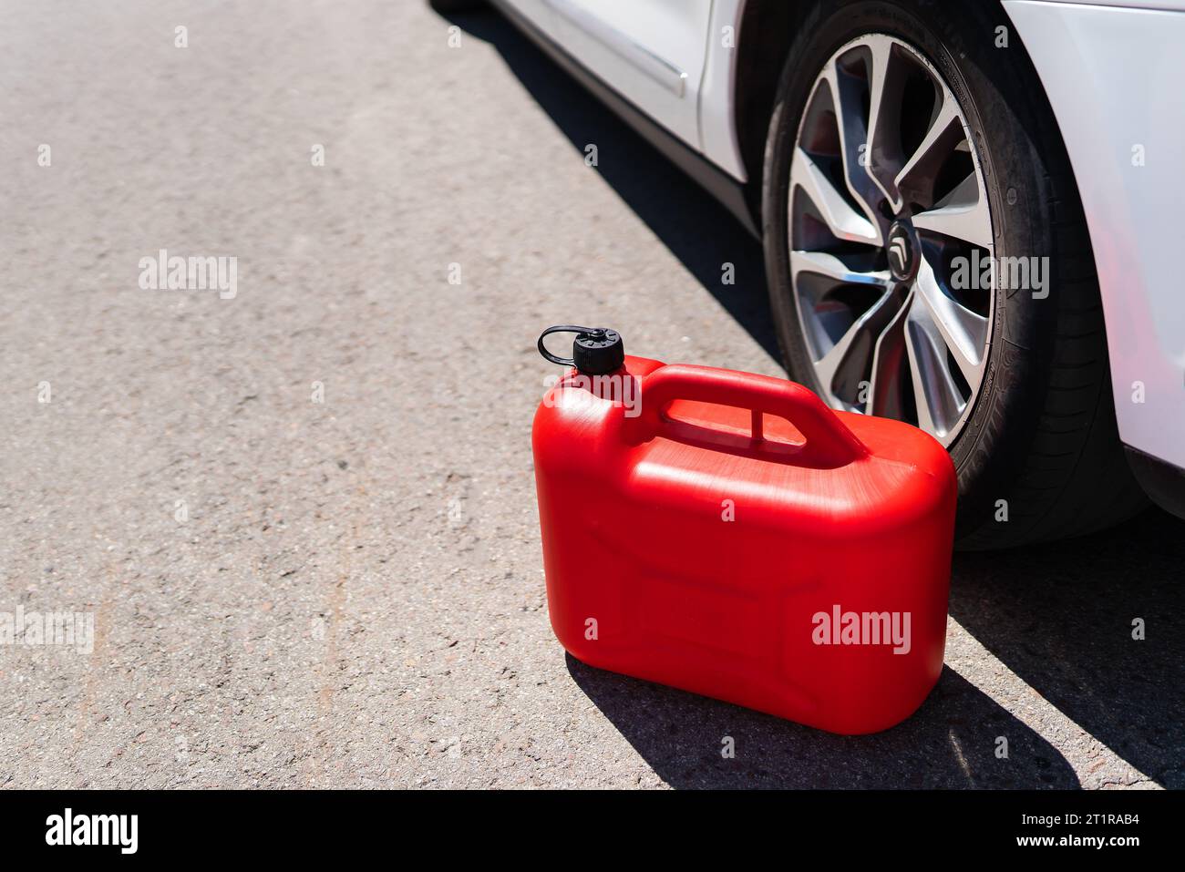 Ein roter Plastikbecher befindet sich mitten auf der Straße neben einem weißen Auto. Probleme beim Betanken Stockfoto