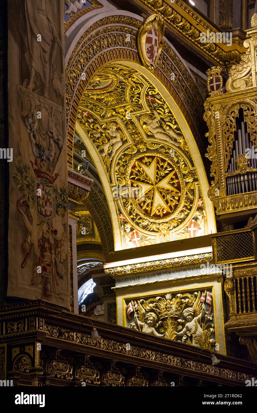 Valletta, Malta - 17. Juni 2023: Detail des goldverzierten Bogens mit dem maltesischen Achtzackkreuz in der Kathedrale von Valletta, Malta Stockfoto