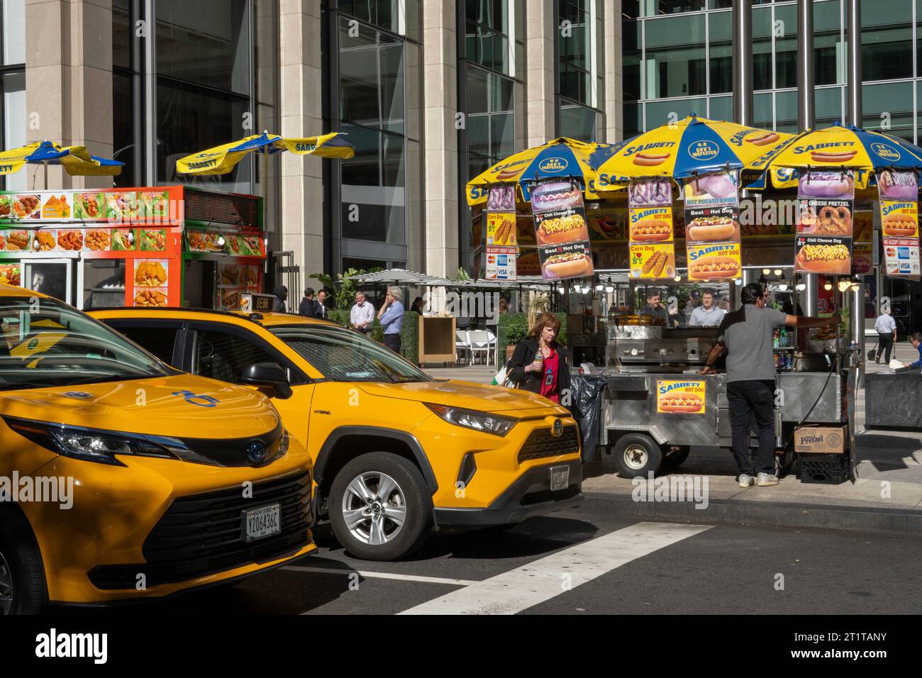 Hotdog-Anbieter und Taxis an einer Kreuzung in Midtown Manhattan an einem sonnigen Herbsttag, 2023, New York City, USA Stockfoto