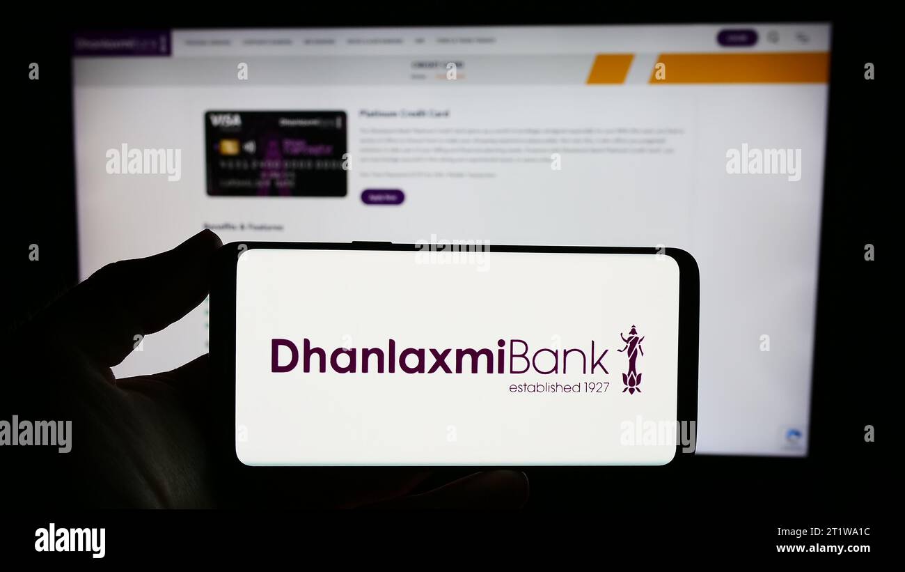 Person mit Smartphone und Logo des indischen Finanzunternehmens Dhanlaxmi Bank Ltd. Vor der Website. Schwerpunkt auf dem Display des Telefons. Stockfoto