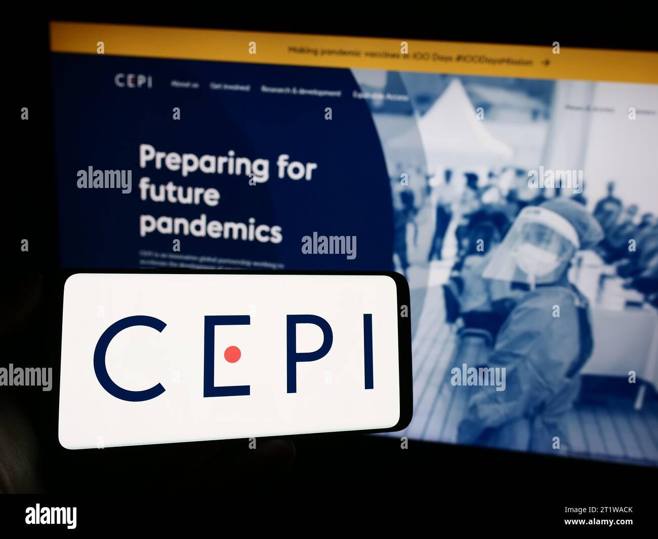 Person mit Handy mit Logo der Koalition für Epidemic Preparedness Innovations (CEPI) vor der Webseite. Schwerpunkt auf dem Display des Telefons. Stockfoto