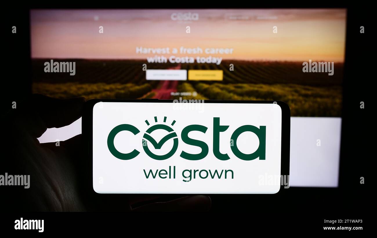 Person mit Smartphone und Logo der australischen Firma Costa Group Holdings Limited vor der Website. Schwerpunkt auf dem Display des Telefons. Stockfoto