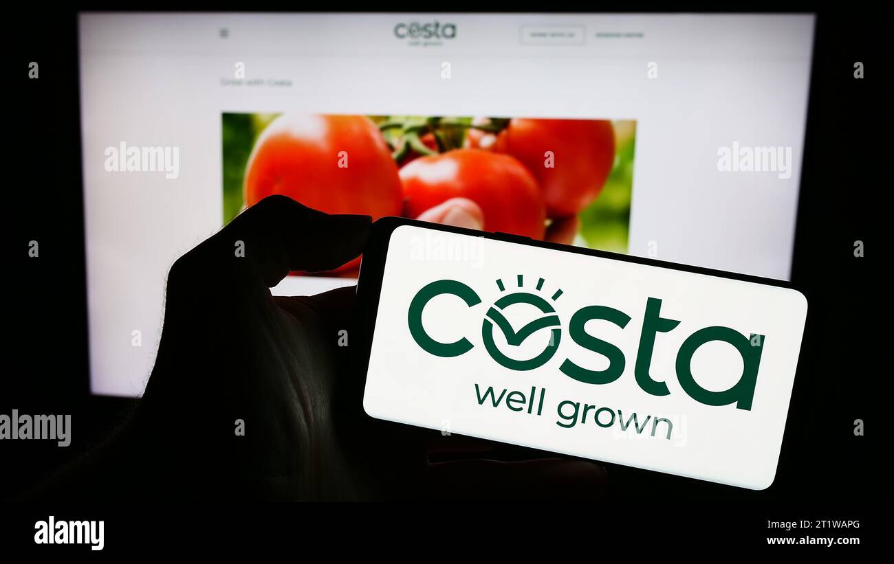 Person, die ein Mobiltelefon mit dem Logo der australischen Firma Costa Group Holdings Limited vor der Webseite hält. Schwerpunkt auf dem Display des Telefons. Stockfoto