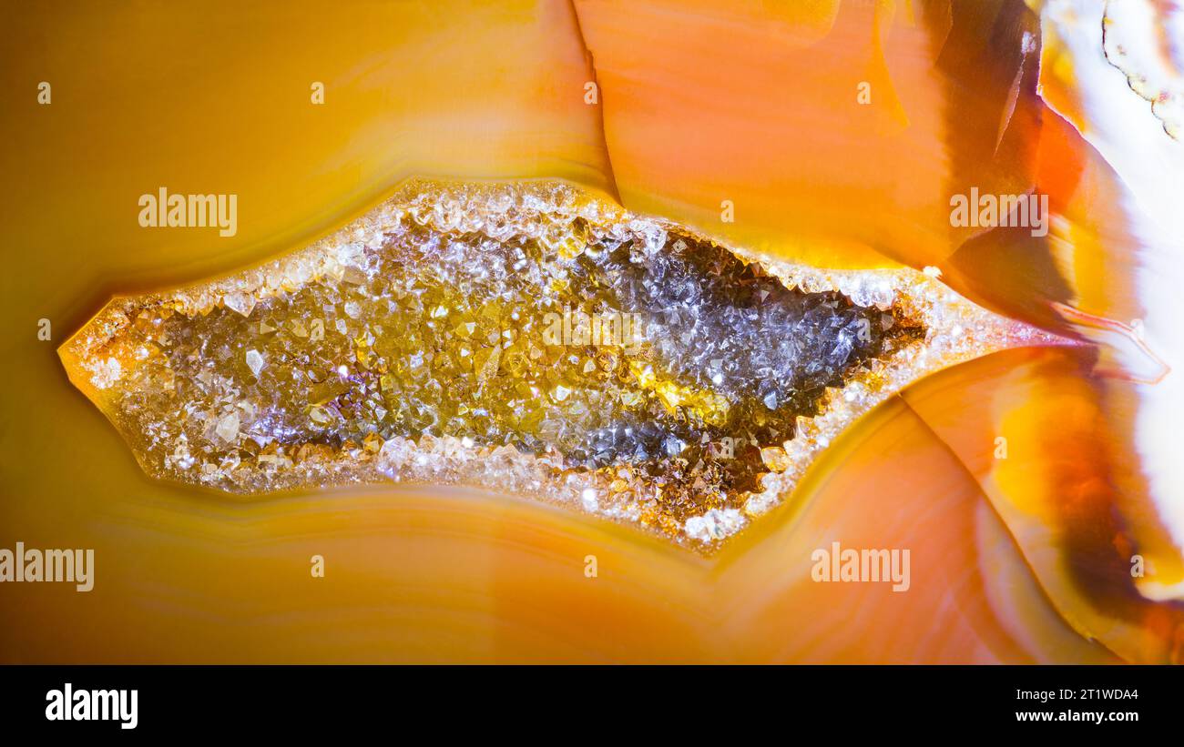 Kleine Geode mit Quarzkristallen im Achat-Edelstein-Querschnitt. Schöner Hohlraum in geschliffenem Edelstein mit goldgelber oder orange polierter Oberfläche. Stockfoto
